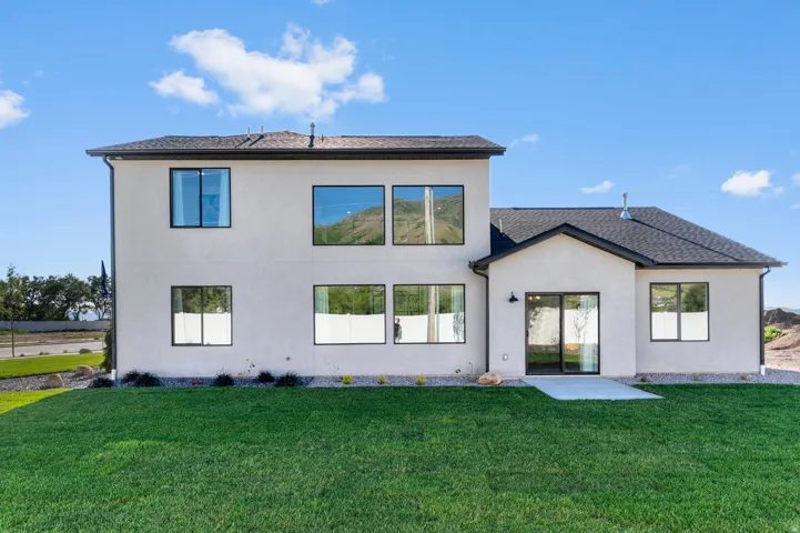 Expansive green lawn with a stucco exterior, black-framed windows, and a glass sliding door