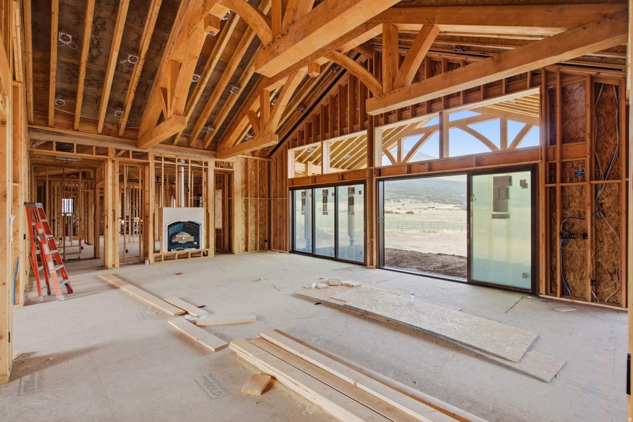 Great Room w/ exposed timber beams in vaulted ceiling, double sliding doors to covered patio