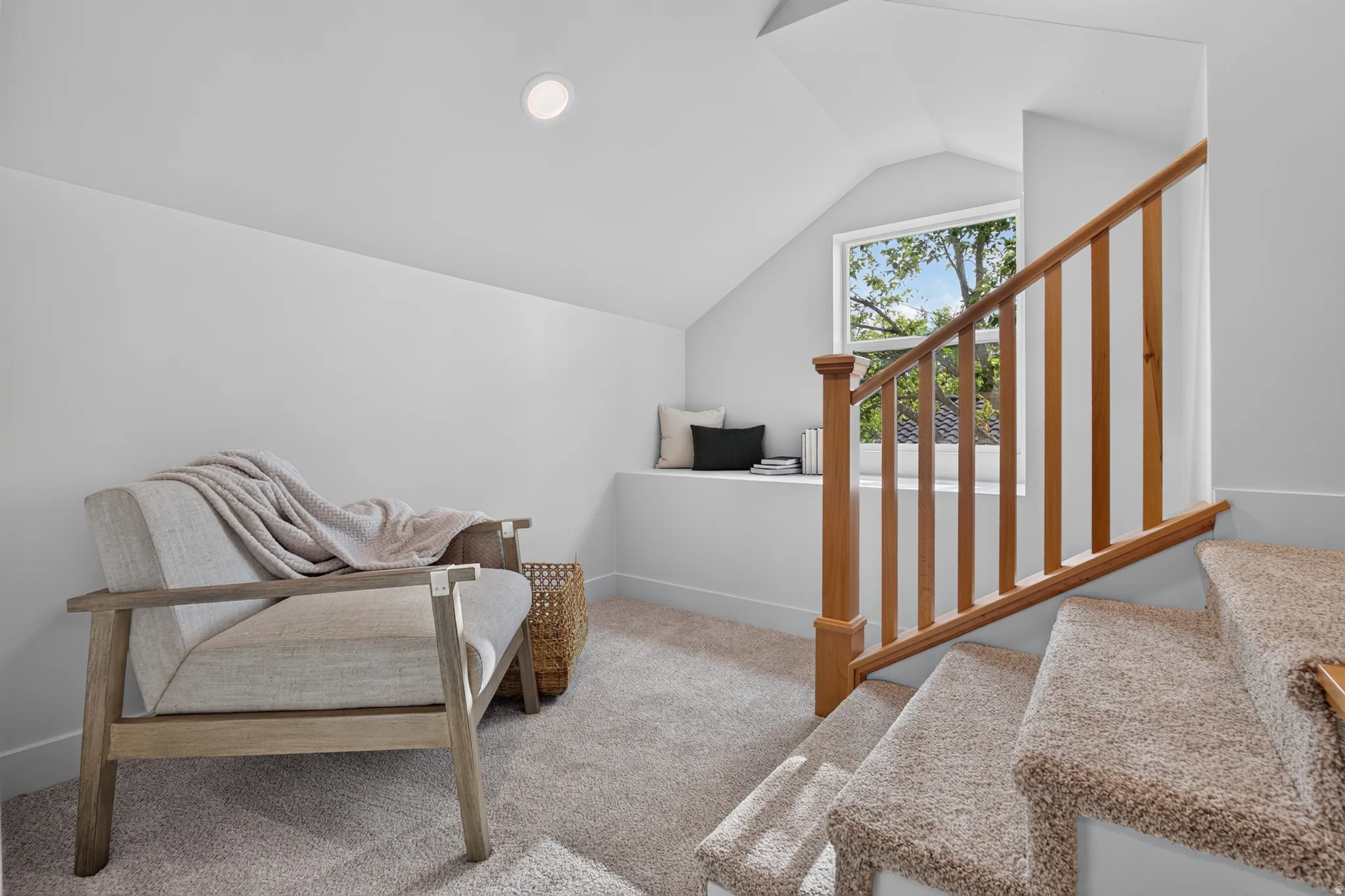 Carpeted staircase with wood banister, recessed lighting, and a built-in window seat