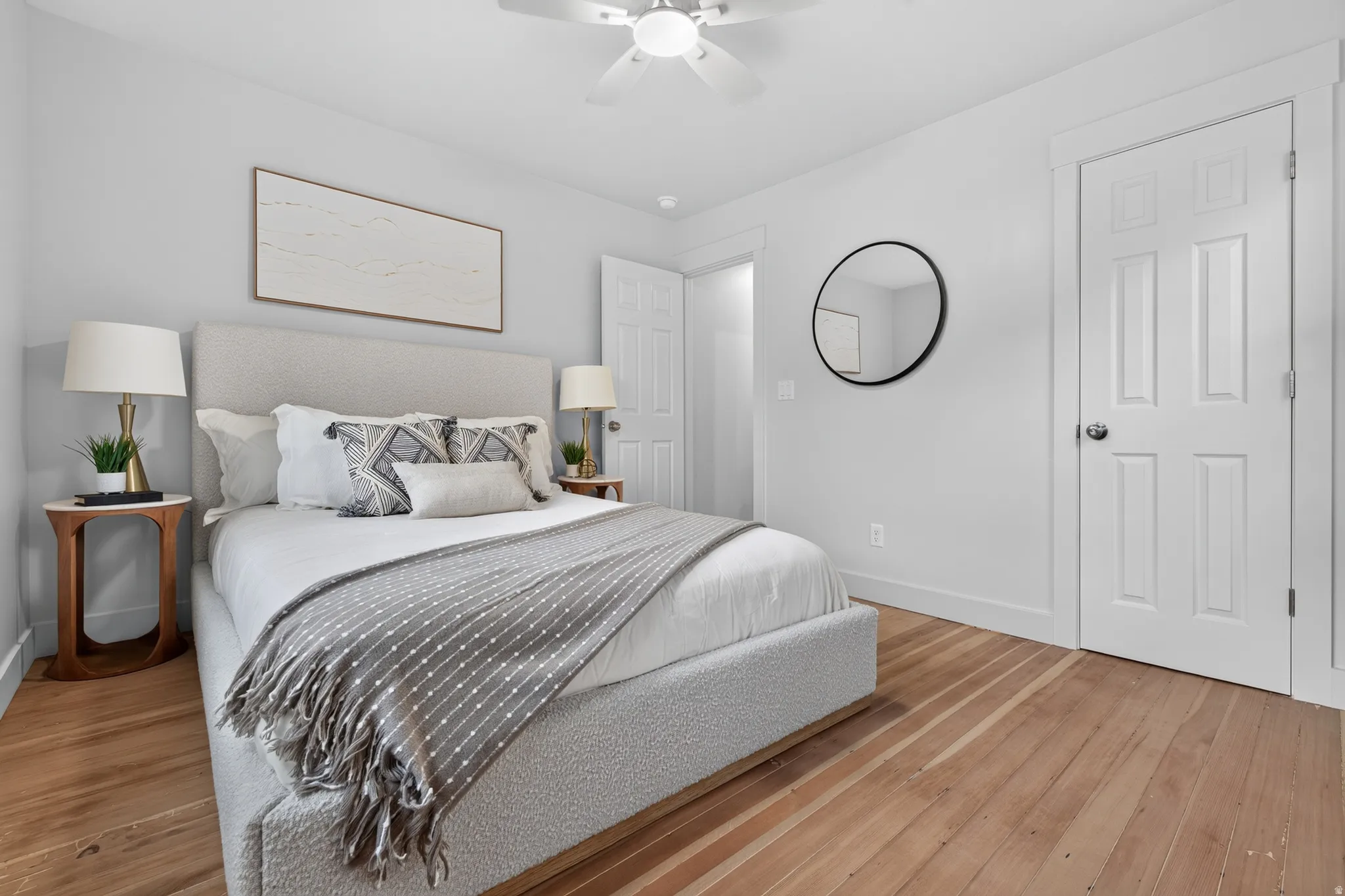 Light-toned walls, wood-finish flooring, white trim, and a ceiling fan with integrated lighting