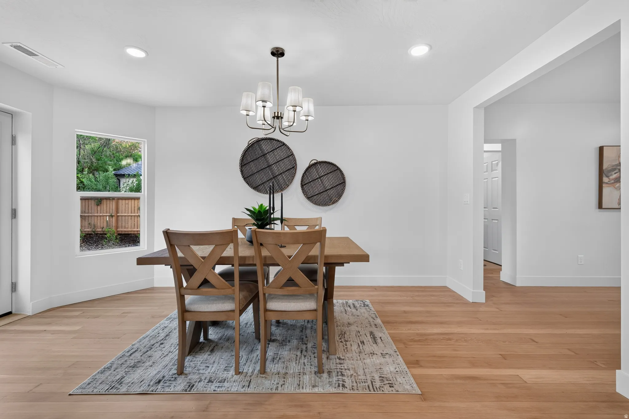 Hardwood flooring, recessed ceiling lighting, a modern chandelier, and a framed window