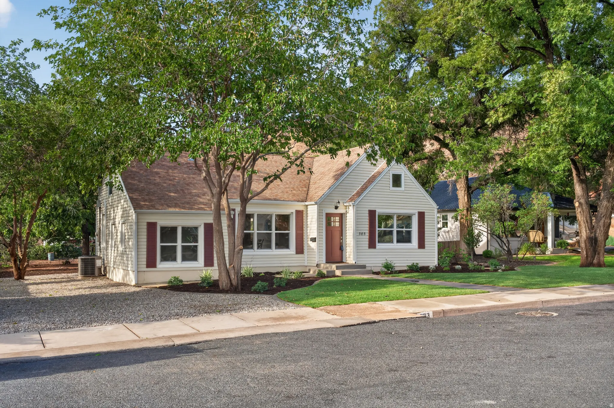 Classic cottage exterior featuring siding, an asphalt shingle roof, red shutters, and a red entry door