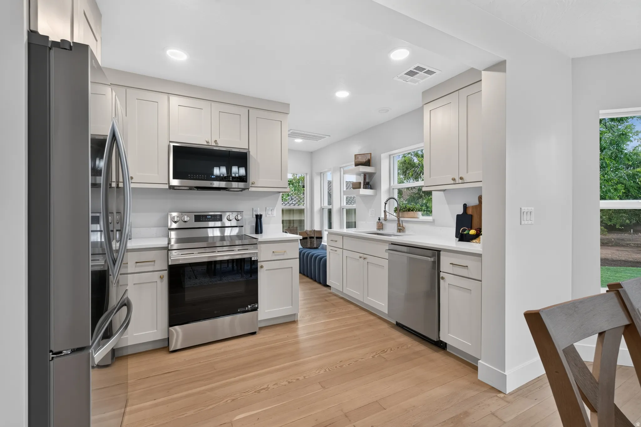 Kitchen featuring light wood-finish flooring, white perimeter cabinetry, stainless steel appliances, and recessed lighting
