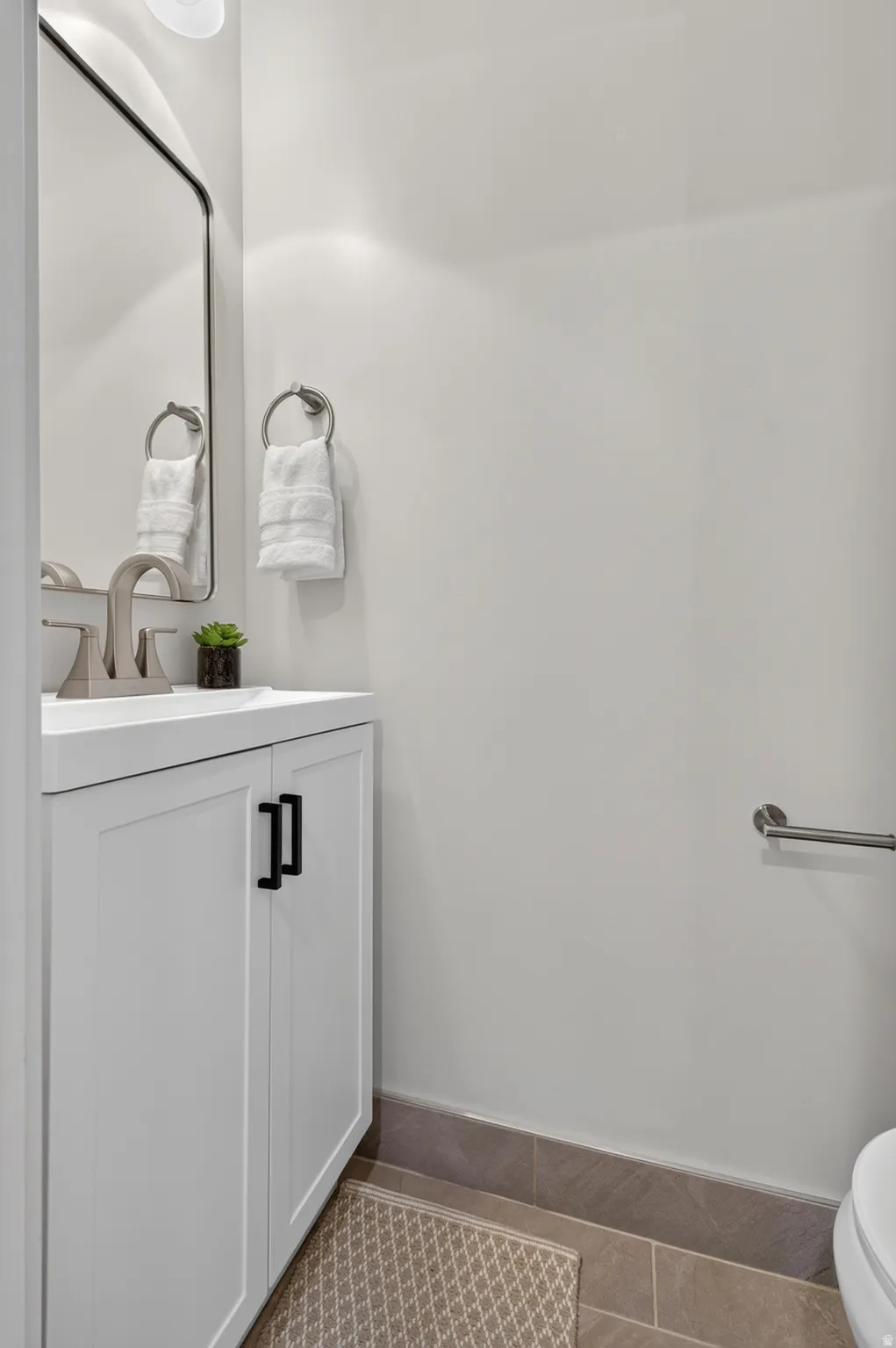 White vanity with black cabinet pulls, undermount sink, and brushed nickel faucet