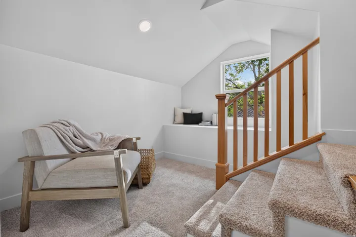 Carpeted staircase with wood banister, recessed lighting, and a built-in window seat