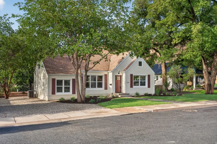 Classic cottage exterior featuring siding, an asphalt shingle roof, red shutters, and a red entry door