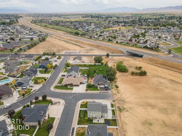 Aerial perspective showcasing residential neighborhood with established homes, paved streets, and undeveloped land