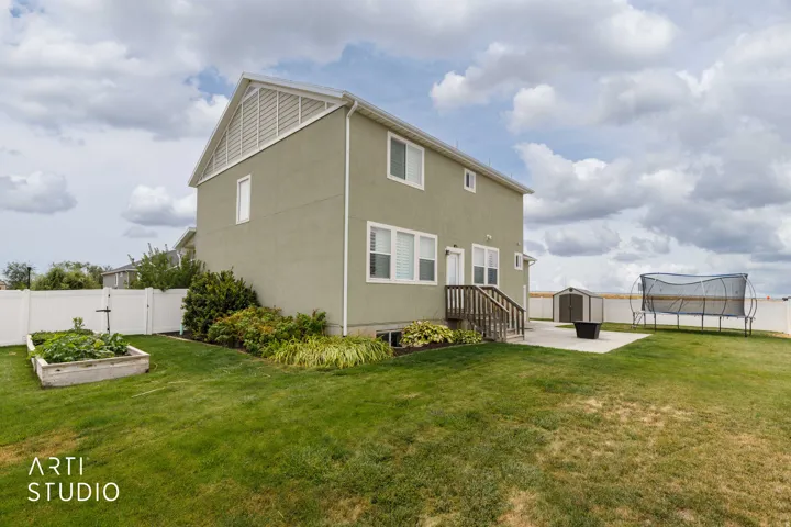 Expansive green lawn with a privacy fence, concrete patio, and garden bed