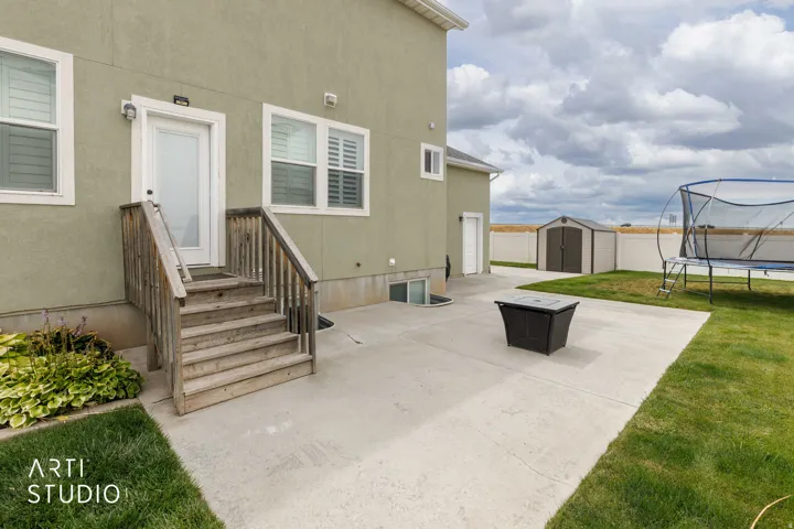 Concrete patio featuring a detached storage shed and a green lawn