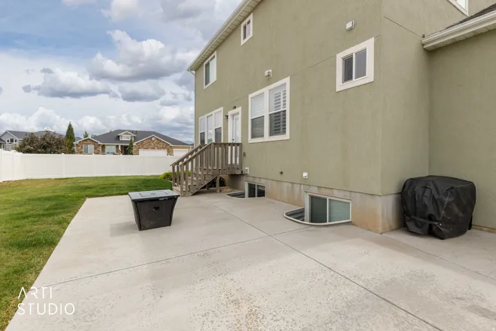 Concrete patio with direct access from the main level, complemented by a white vinyl fence enclosing a grass lawn