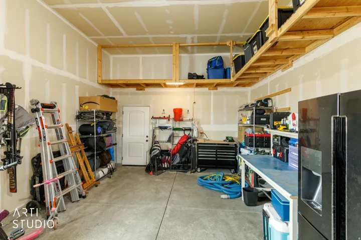 Overhead wooden shelving for storage, durable concrete flooring, and an integrated workbench surface