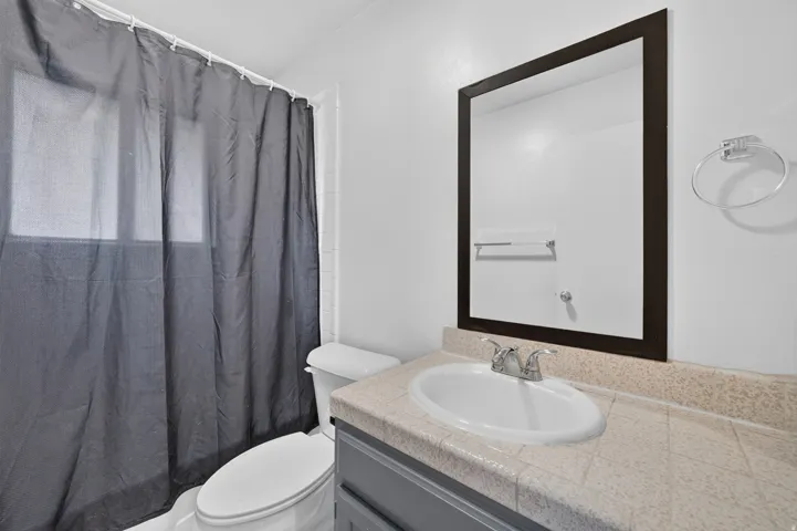 Vanity with an integrated sink, tile countertop, and mounted mirror