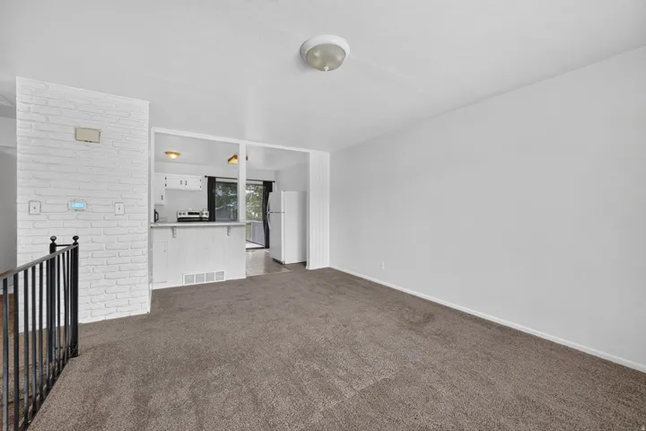 Open-concept living area with neutral carpet flooring and white painted walls