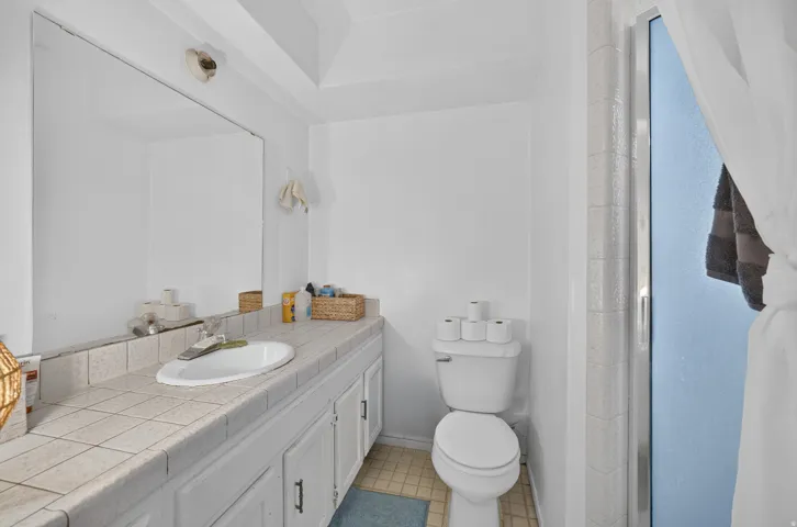 Vanity with integrated sink, tile countertop, and extensive storage cabinetry
