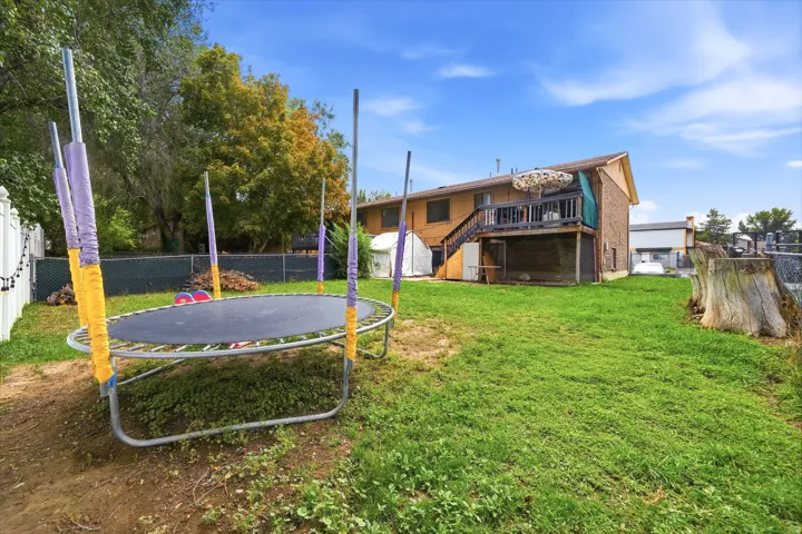 Expansive backyard with a manicured lawn, wood deck, and a privacy fence
