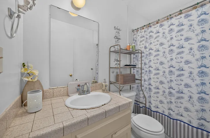 Vanity with tiled countertop, undermount sink, and wall-mounted mirror