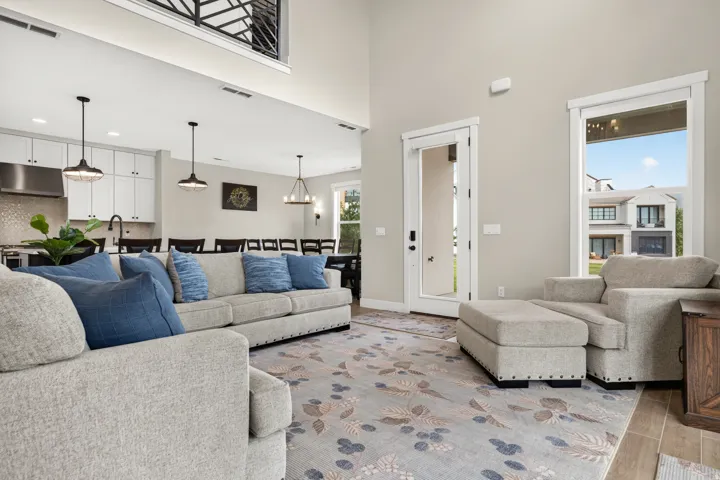 Open-concept living space with high ceilings, recessed lighting, wood-finish flooring, and a second-story balcony