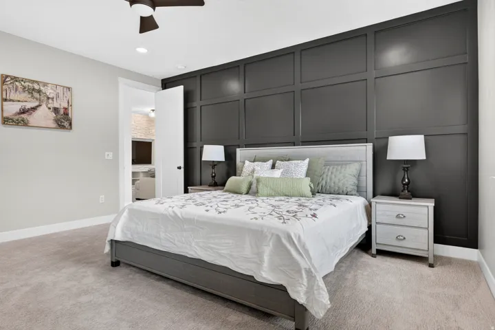 Accent wall with panel molding, light-toned carpeting, ceiling fan, recessed lighting, and a white interior door