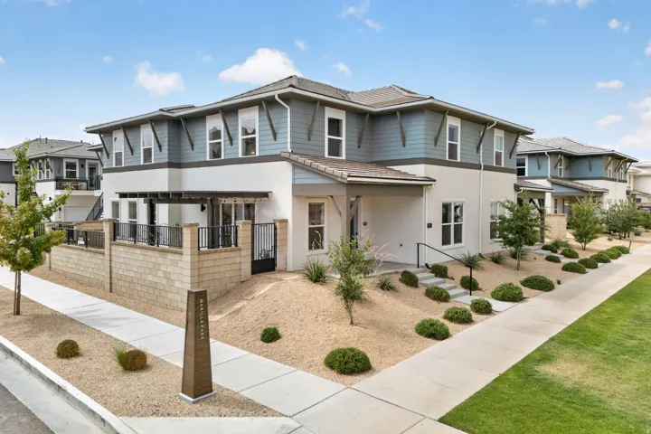 Two-story stucco and siding exterior with covered entry, multiple windows, and a paved walkway