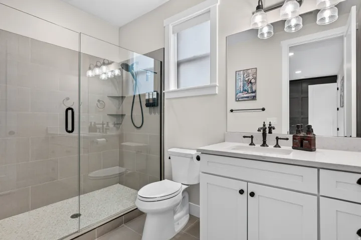Glass-enclosed shower with tile surround and mosaic floor