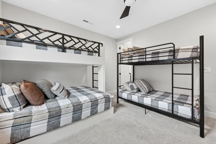 Built-in bunk beds with decorative metal railing, additional metal bunk bed, recessed lighting, and a ceiling fan