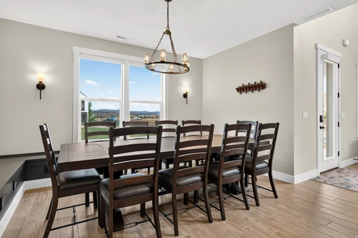 Open concept dining space with large window, wood-finish flooring, and chandelier