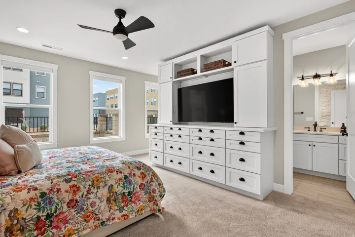Recessed lighting, ceiling fan, built-in cabinetry with integrated shelving, multiple windows, and a bathroom vanity with dual sinks