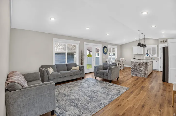 Open-concept living space featuring wood-finish flooring, recessed lighting, and a kitchen island with a waterfall countertop