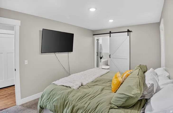 Recessed lighting, light gray wall finishes, white trim, and a white barn door