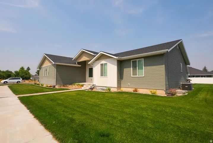 Contemporary residence featuring a blend of horizontal siding and vertical paneling, a dark shingle roof, and a concrete pathway leading to the entry