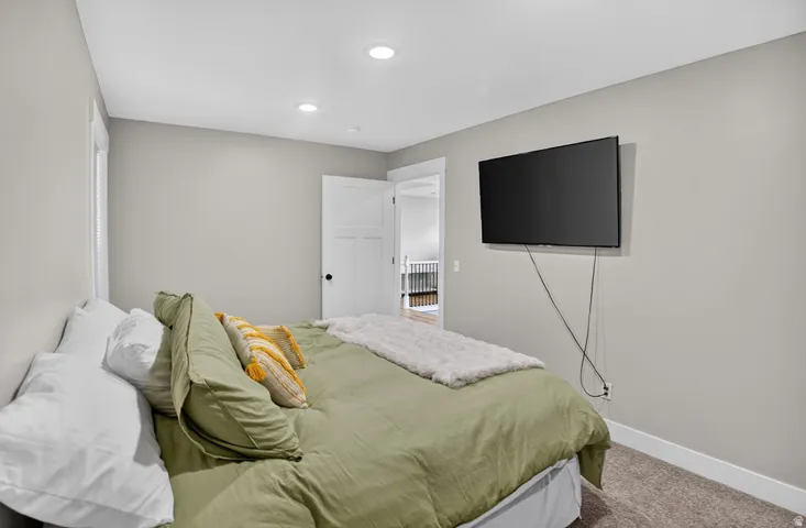 Recessed ceiling lighting, carpet flooring, wall-mounted display, and white trim