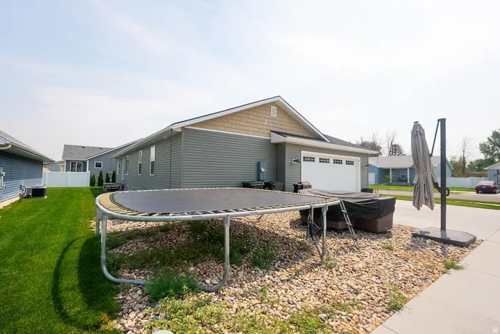 Manicured lawn, side-entry garage, tan shake siding, gray horizontal siding, white privacy fence