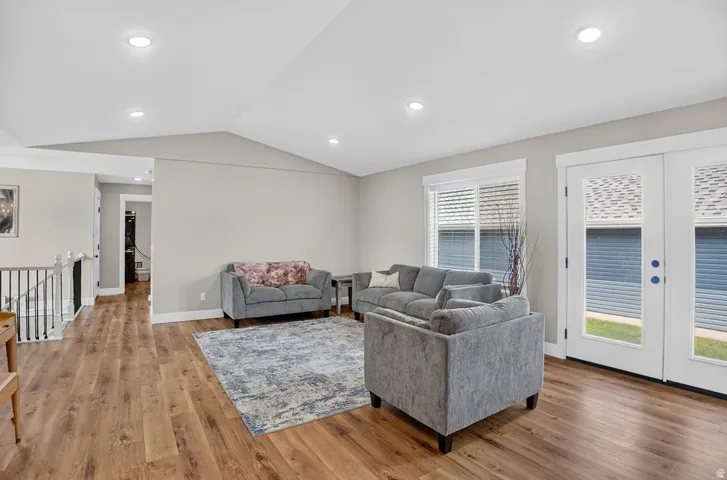 Wood-finish flooring, recessed lighting, white trim, and a white railing with black spindles