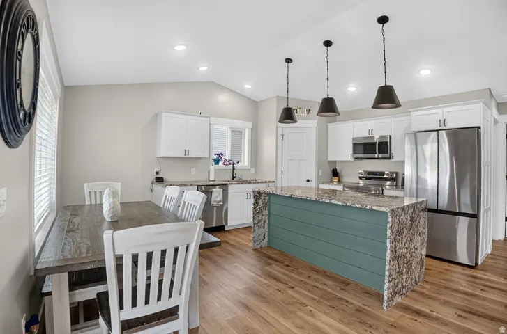 Kitchen featuring white cabinetry, stainless steel appliances, a center island with a stone countertop, wood-finish flooring, and recessed lighting