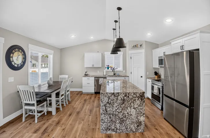 Kitchen featuring an expansive center island, stainless steel appliances, white cabinetry, wood-finish flooring, and recessed lighting