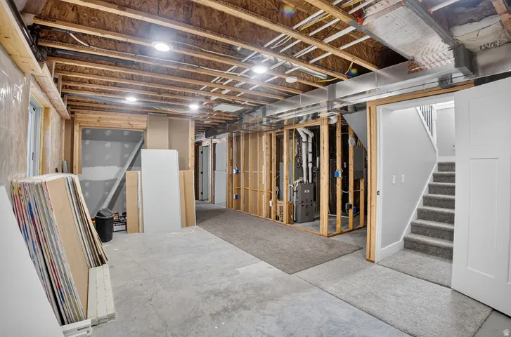 Unfinished basement featuring exposed wood joists, concrete flooring, and partial wall framing
