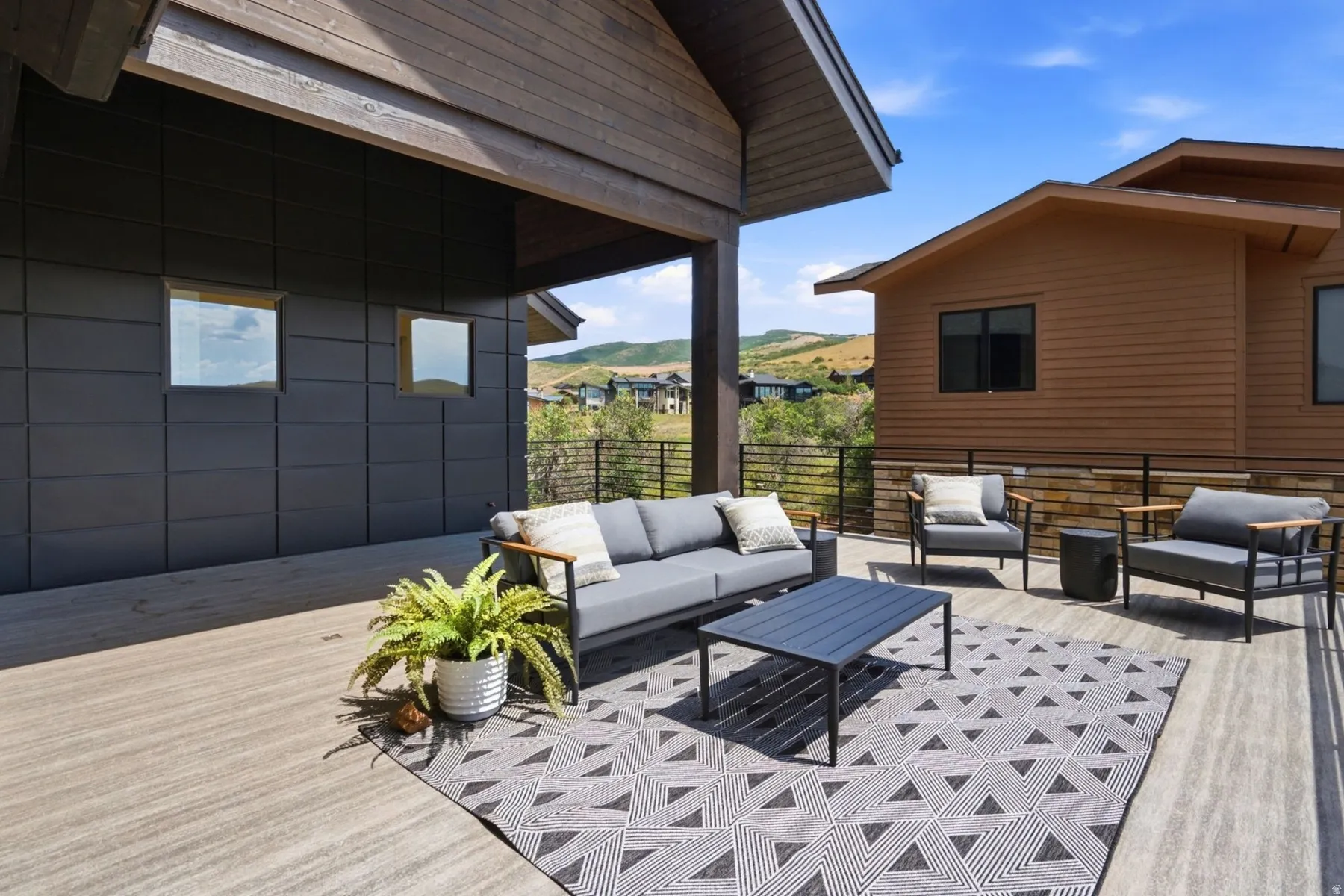 Expansive outdoor deck with composite flooring, a covered patio area, and a horizontal metal railing