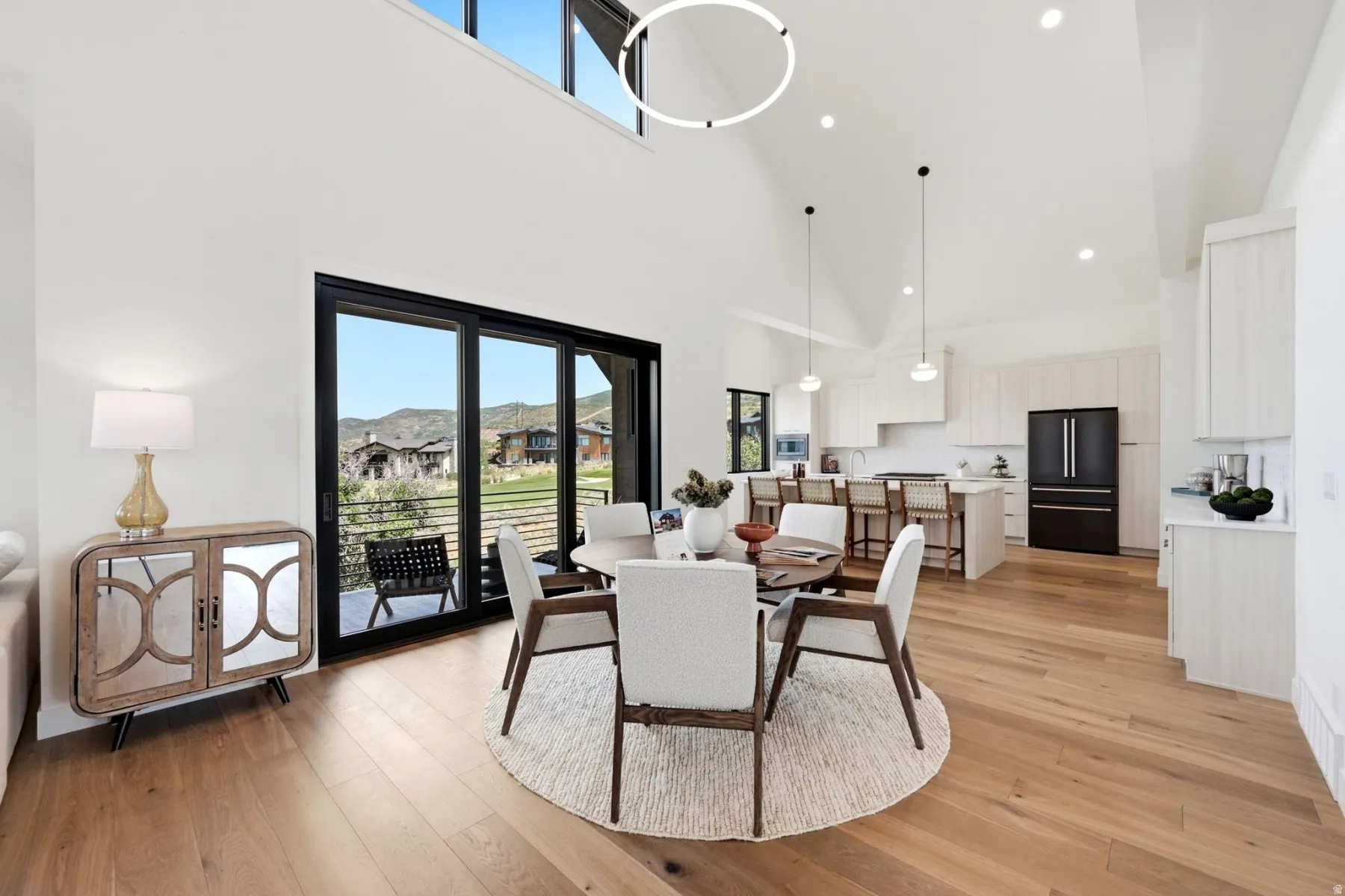 Vaulted ceilings, large sliding glass doors, upper transom windows, wood-finish flooring, and a contemporary kitchen with a center island