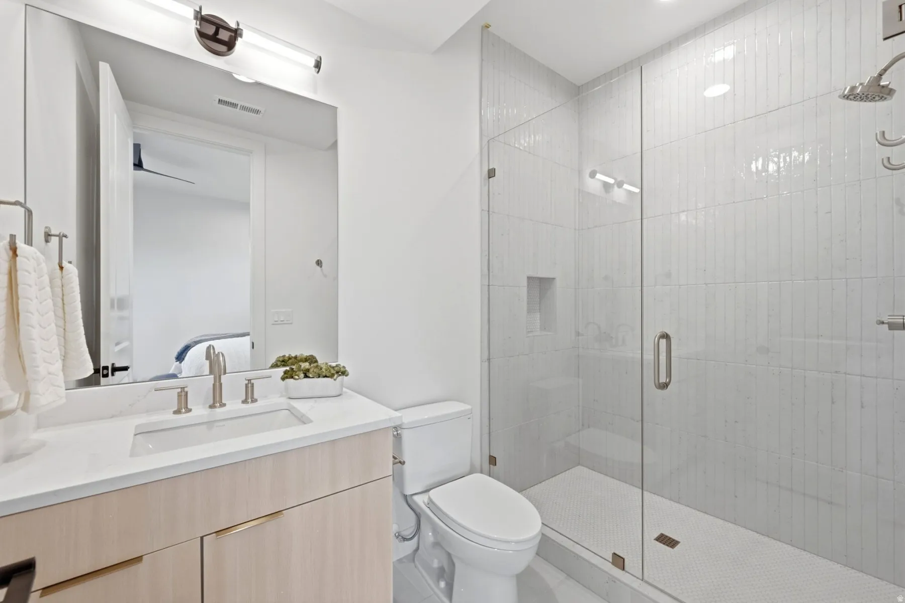 Modern bathroom featuring a glass-enclosed shower with vertical tile, a built-in shower niche, and a rain showerhead