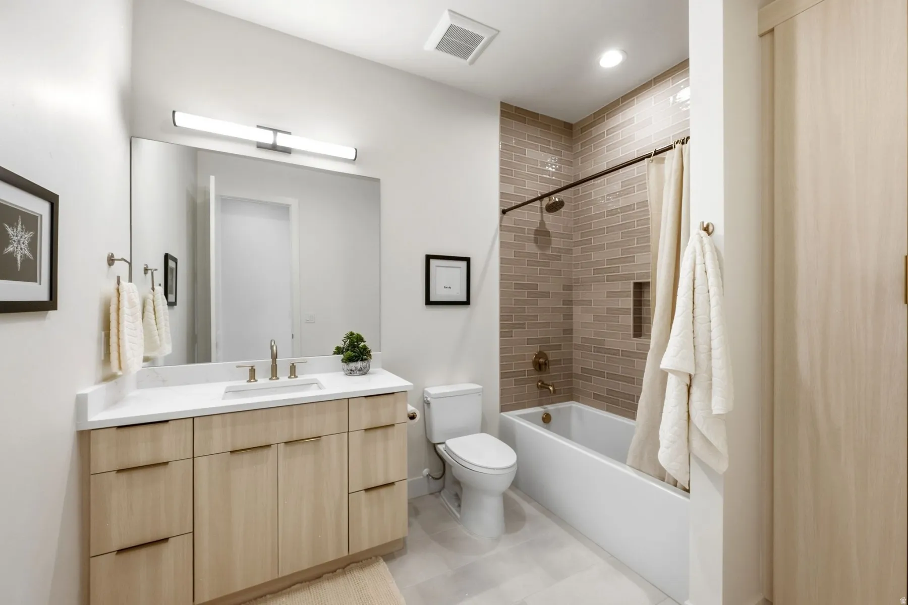 Spacious bathroom featuring a single vanity with light wood-finish cabinetry, a white countertop, and a large mirror