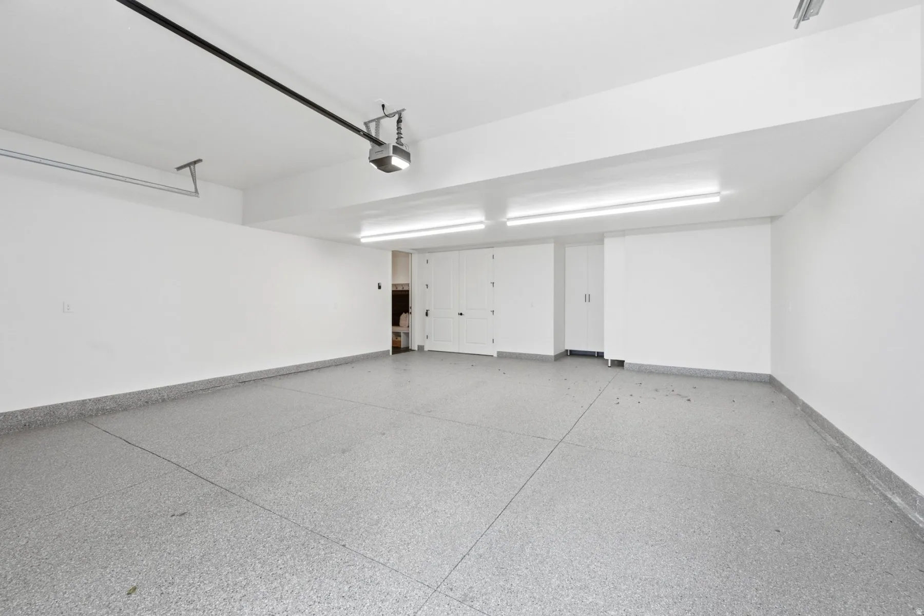 Garage featuring an epoxy coated floor, built-in storage cabinetry, and overhead lighting