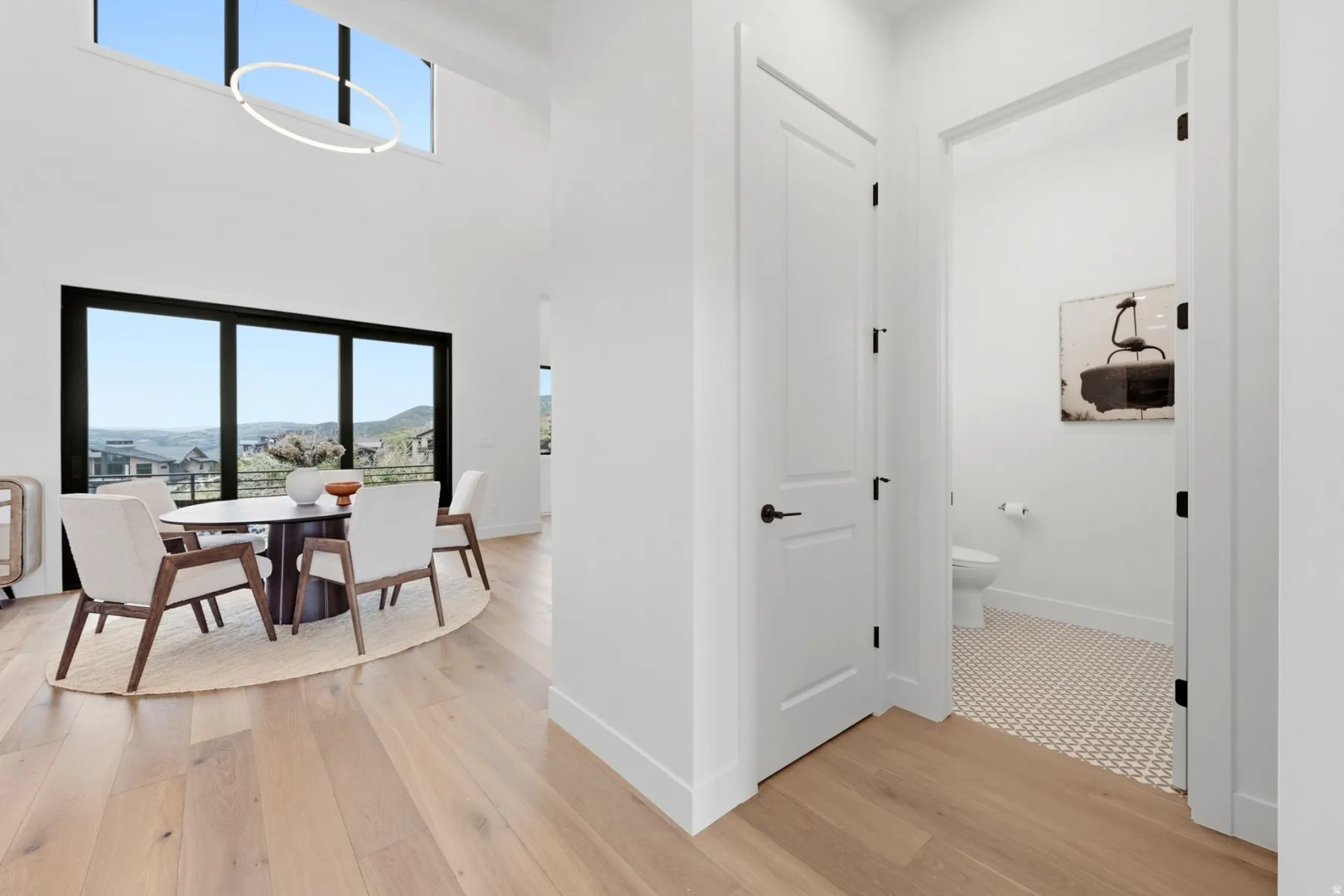 High ceilings with an upper window, large dark-framed windows, and light wood-finish flooring