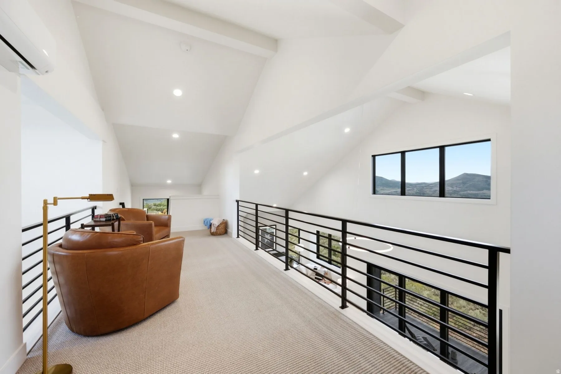 Vaulted ceilings with exposed beams, recessed lighting, and a black metal railing system