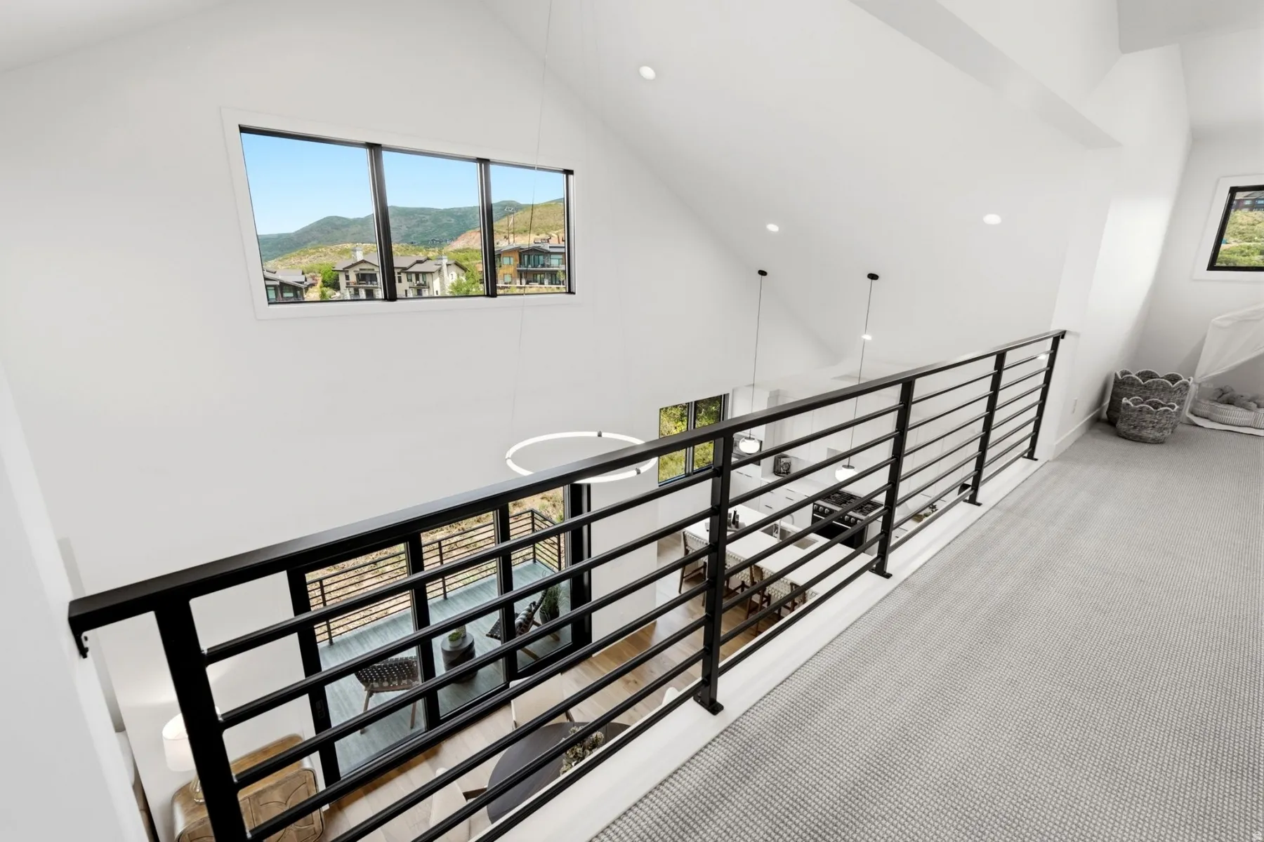 Loft area featuring a black horizontal bar railing, neutral-toned carpet, recessed lighting, and a large window