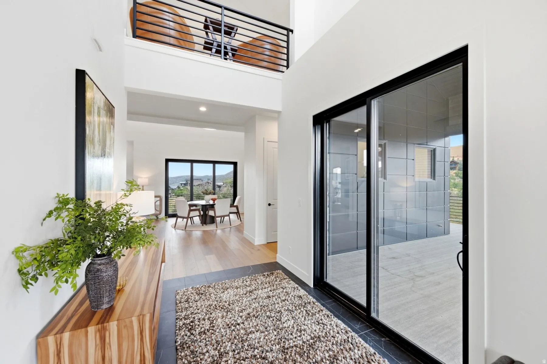 Two-story foyer with a decorative open railing, wood-finish flooring, and a sliding glass door