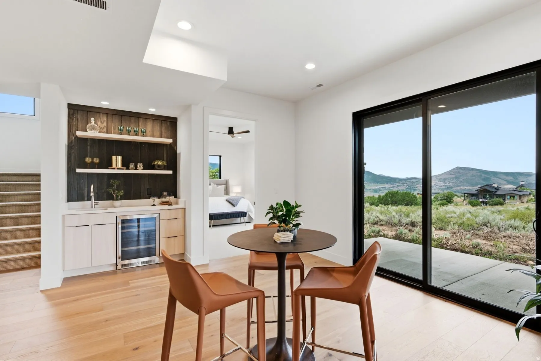 Built-in wet bar with wood-finish paneling, under-counter refrigeration, and open shelving