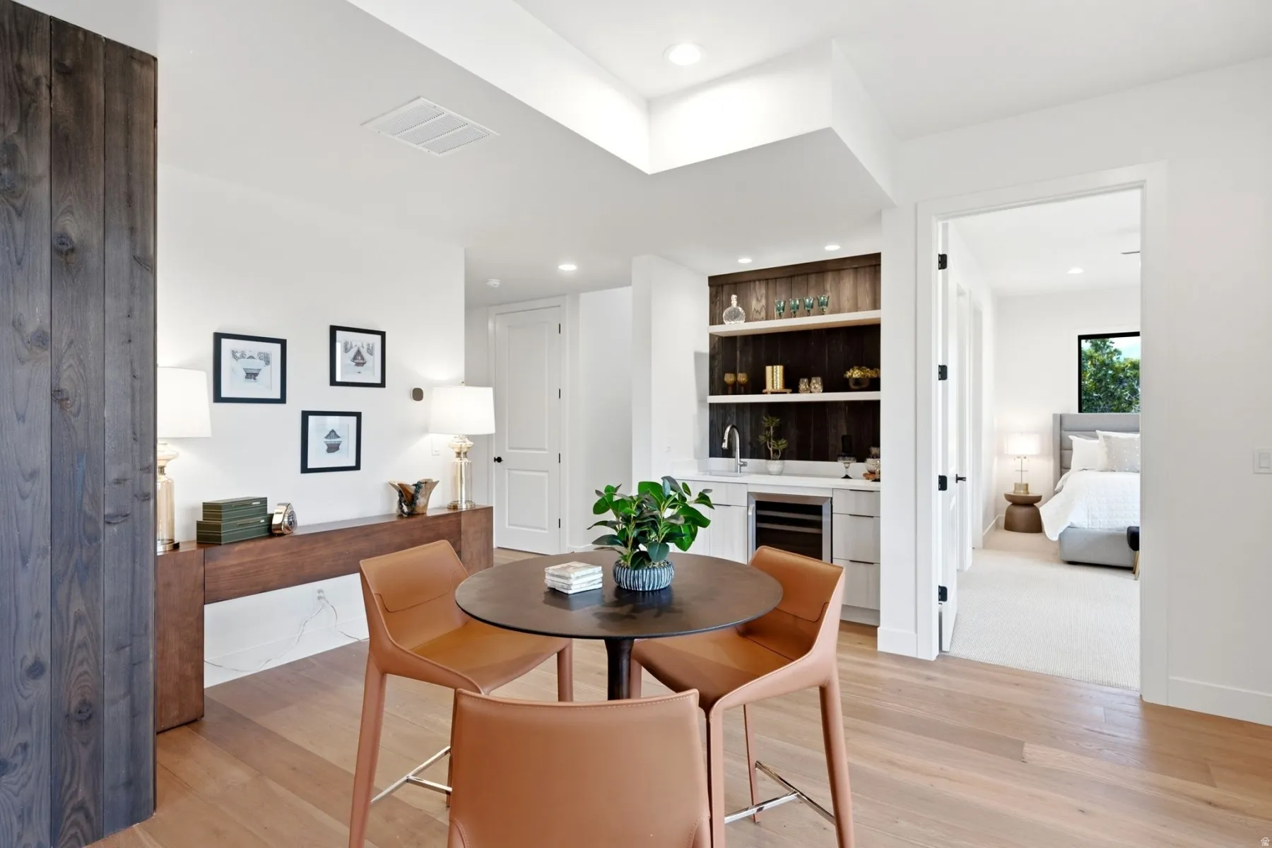 Light wood-finish flooring, built-in wet bar with shelving, integrated beverage cooler, and recessed lighting