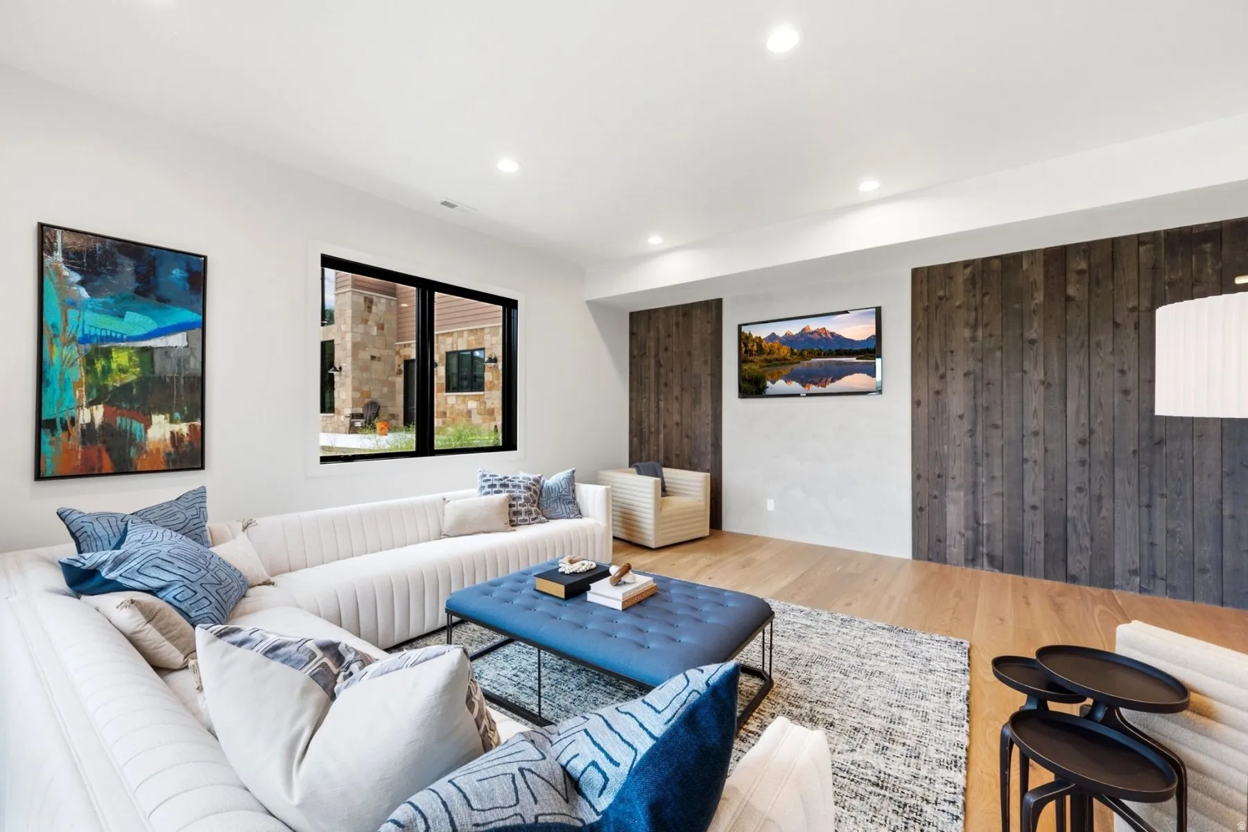 Recessed lighting illuminates the space, featuring wood-finish flooring and a window with black trim