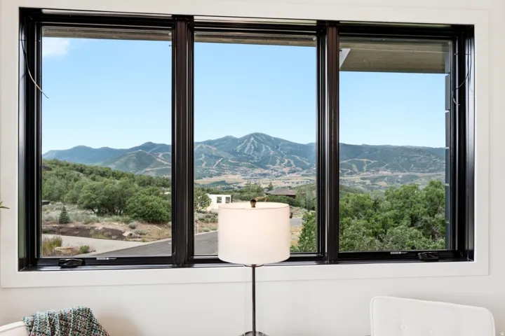 Expansive mountain scenery visible through large multi-pane windows with black frames and white trim