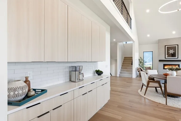 Extended wood-finish cabinetry with linear hardware, white subway tile backsplash, and light-toned countertops